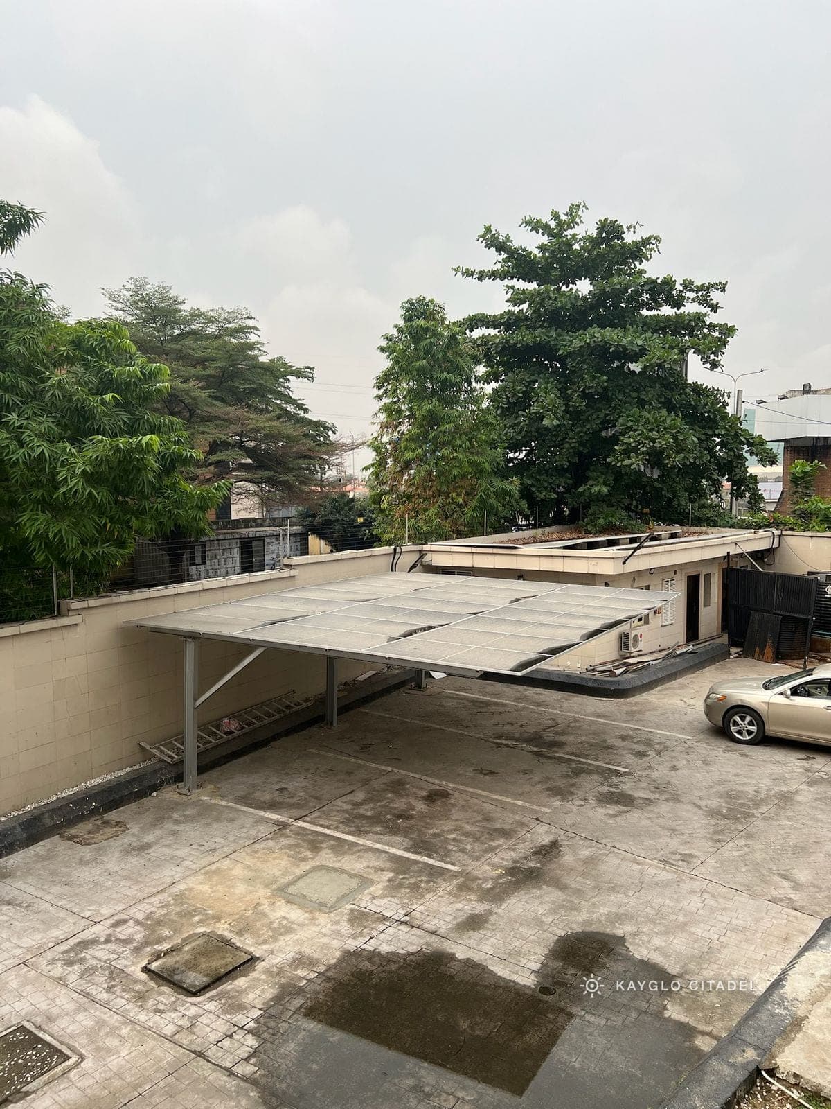 Completed solar carport shading the parking court, seen from an upper floor.