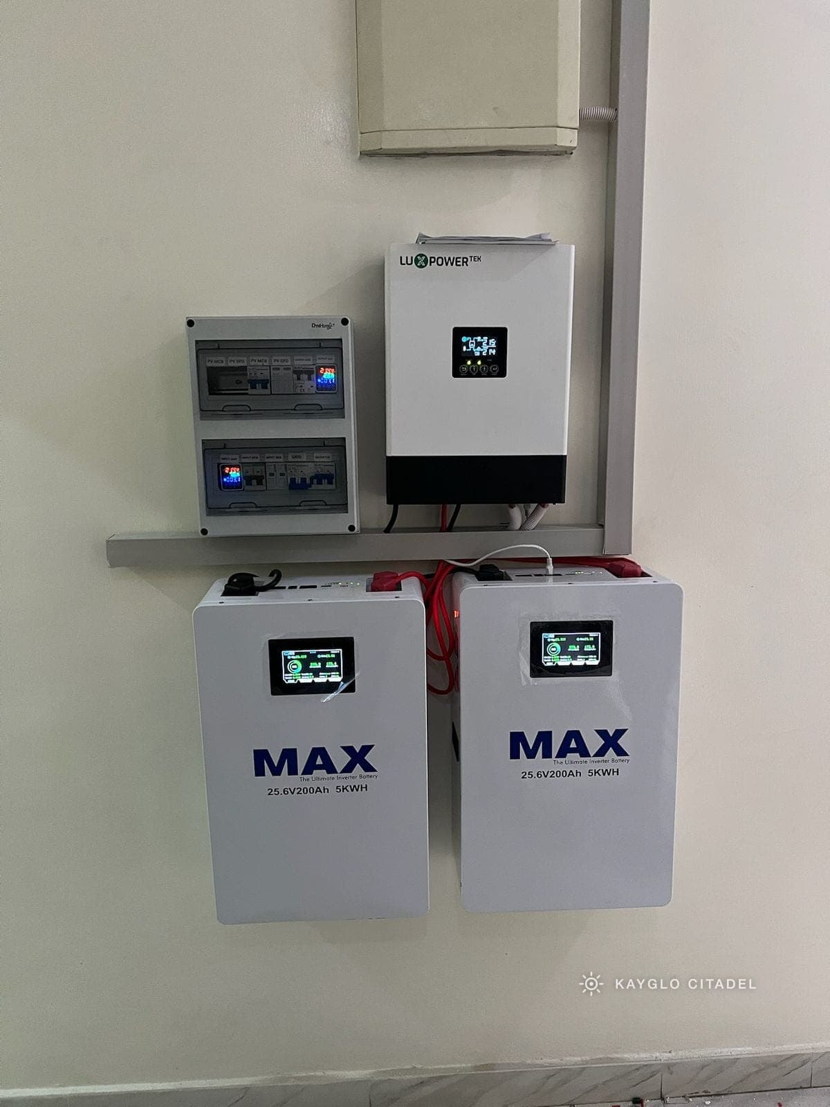 A hybrid inverter, distribution board and lithium batteries on a plant-room wall.